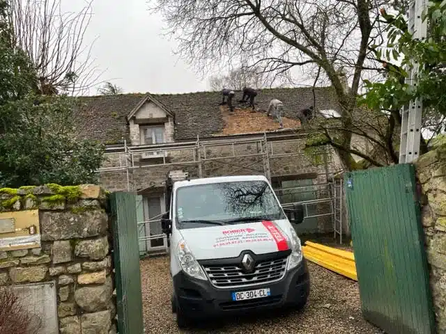 Véhicule de M Robert devant un maison dont la couverture est entrain d'être rénovée